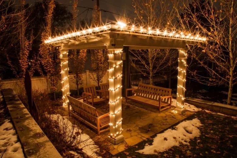 A garden gazebo wrapped in warm white holiday lights