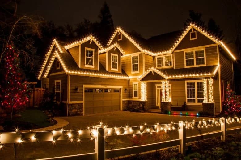 A home sparkling with warm white Christmas lights from its roofline to the front walkway